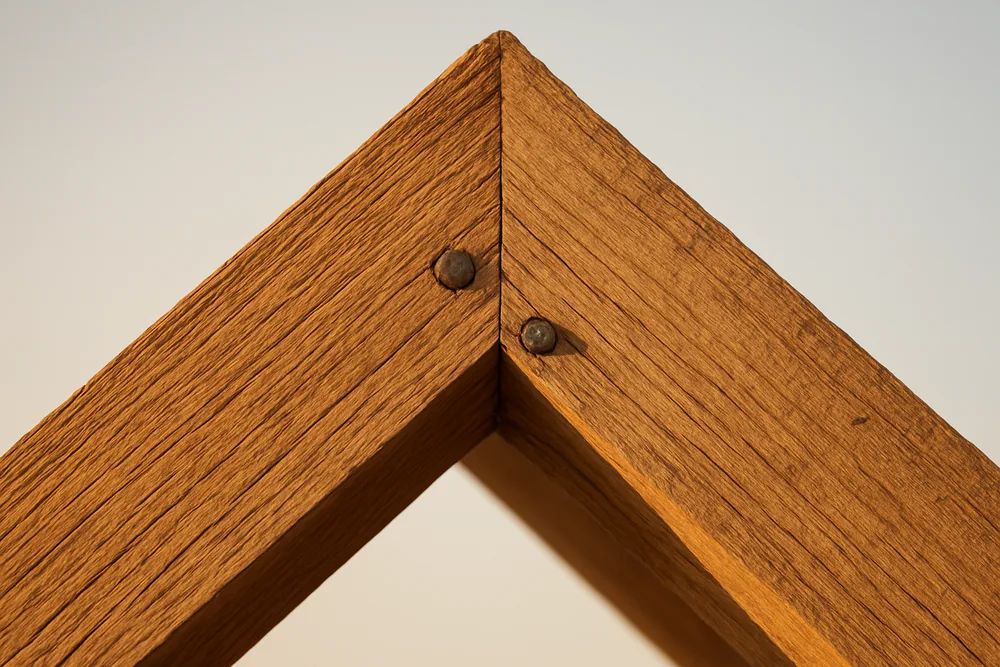 A close crop of two bare timber rafters nailed together at the apex — pole barn, Tyler. Illustrative example.